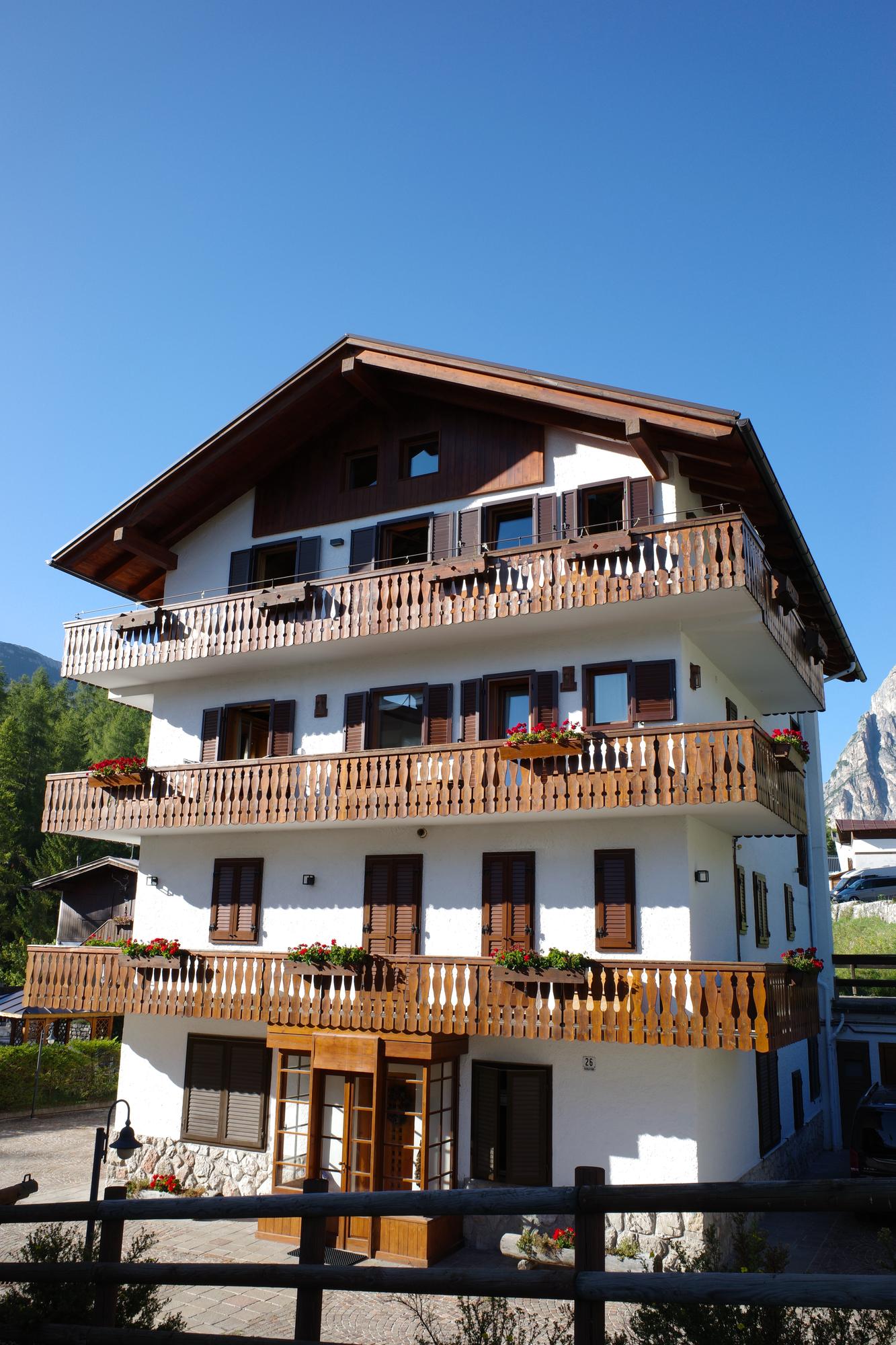 A tall alpine hotel with wooden balconies full of red geraniums