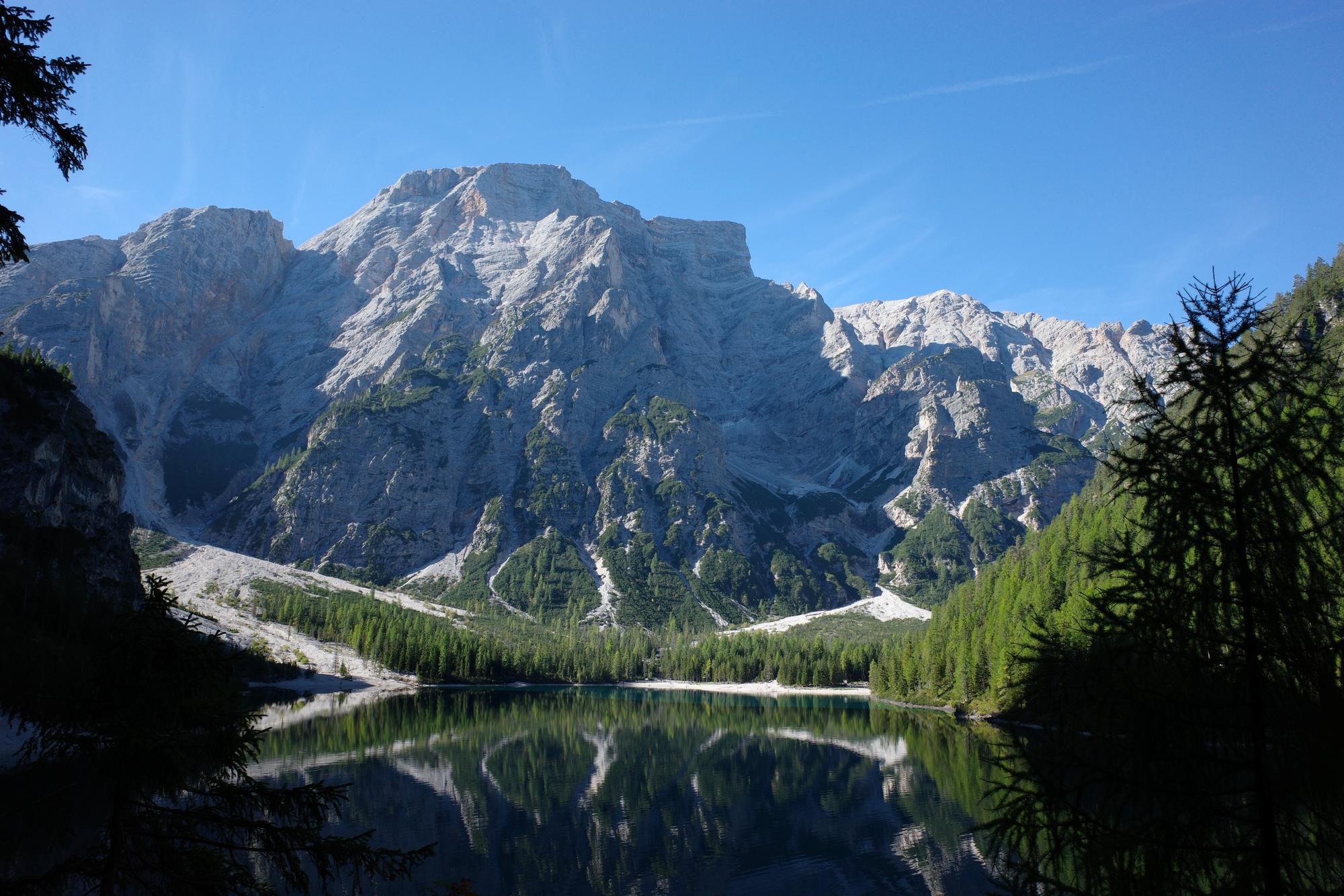 A limestone massif mirrored in the still surface of an alpine lake in the Dolomites