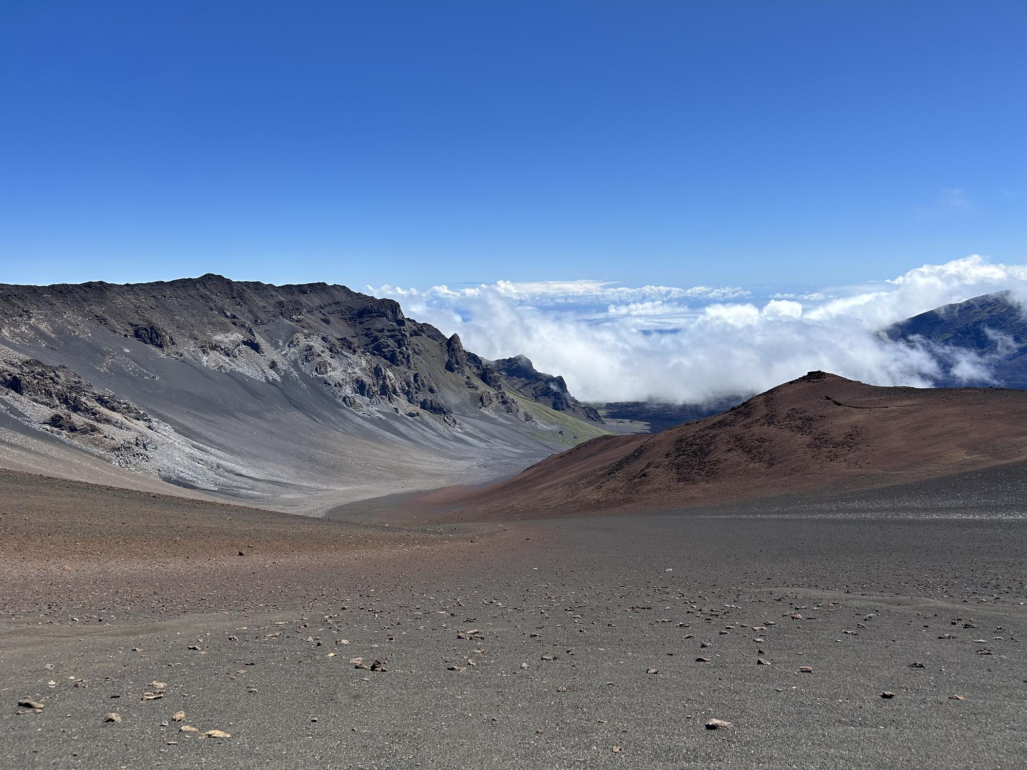 The volcanic expanse of Haleakala crater on Maui with clouds spilling over the rim