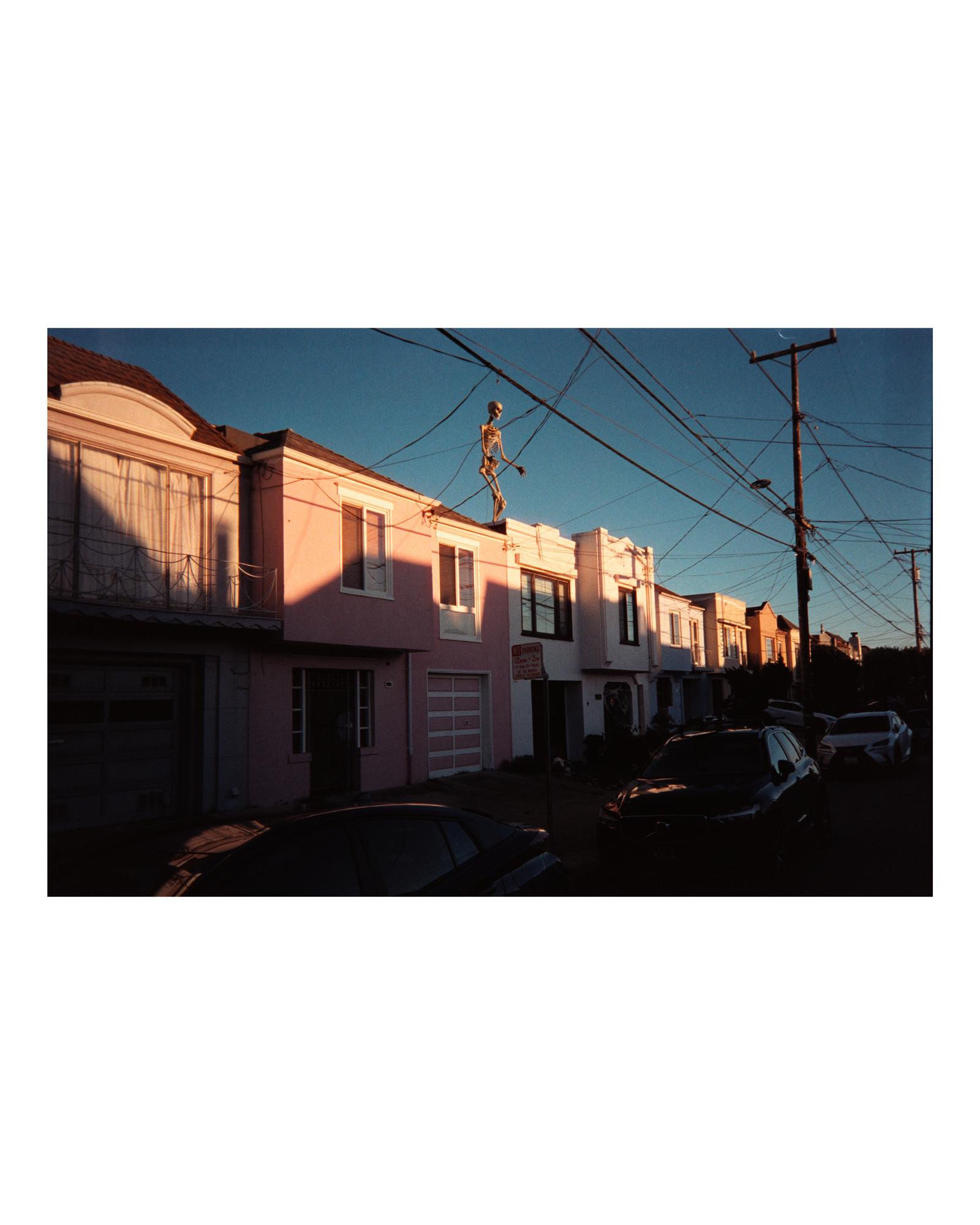 Pastel San Francisco houses with a skeleton figure posed on a power line